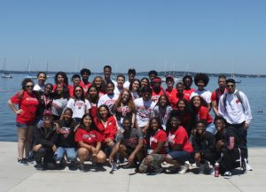 A large group of Posse scholars pose for a photo with Lake Mendota in the background.